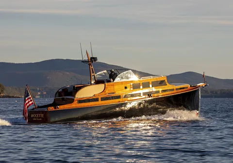 Wooden commuter yacht running in profile at sunset